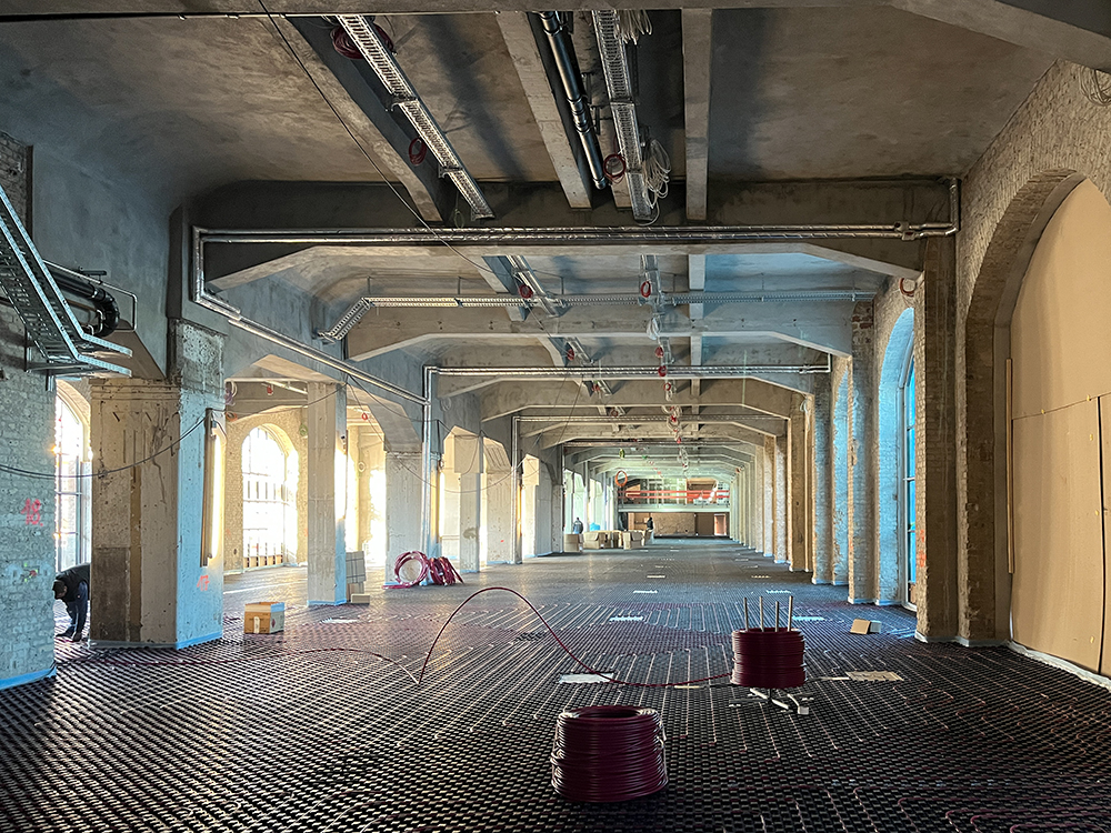 Fortschritt der Bauarbeiten im Postbahnhof Berlin, große Fenster und strukturierte Böden sind sichtbar.