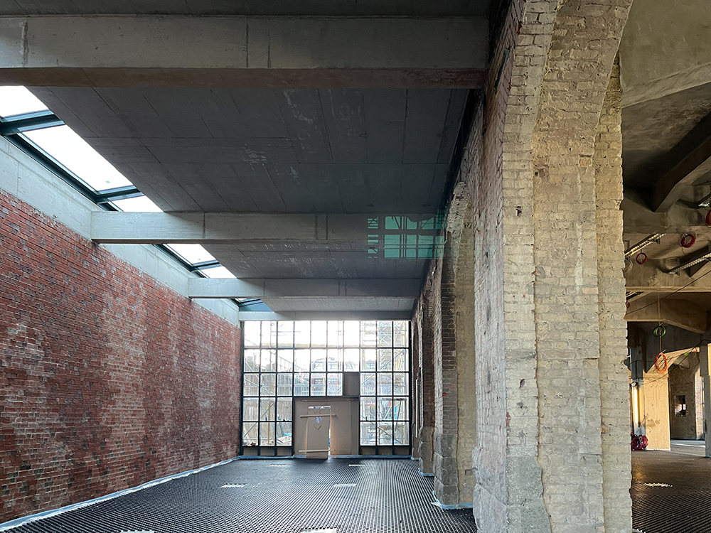 Innenansicht des Postbahnhofs mit Ziegelwänden und großen Fenstern.
