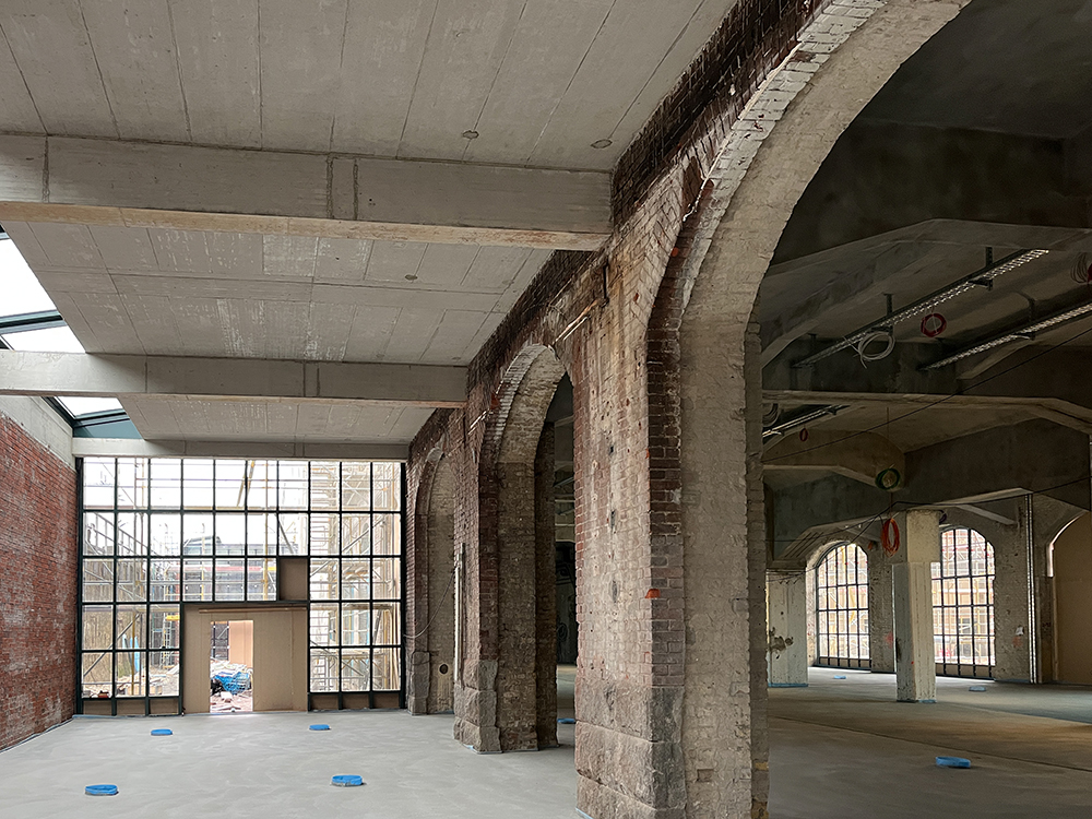 Innenansicht des Baufortschritts im Postbahnhof Berlin mit sichtbaren Ziegelwänden und Fenstern.