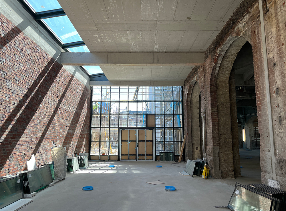 Innenansicht des Baufortschritts im Postbahnhof Berlin mit sichtbaren Ziegelwänden und Fenstern.