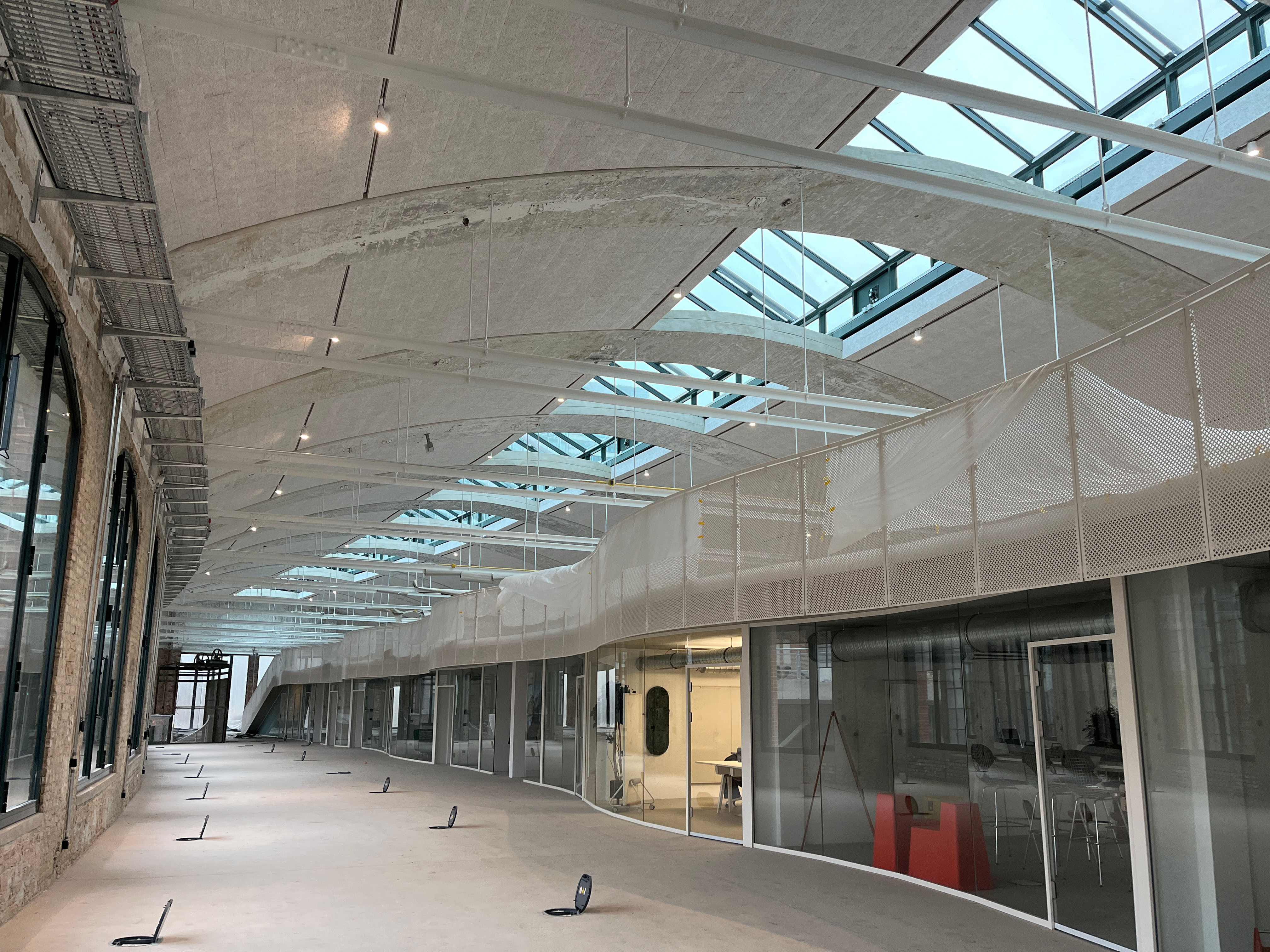 Langer Innenraum der Eingangspackkammer mit Glasdecke und Baustellenequipment.