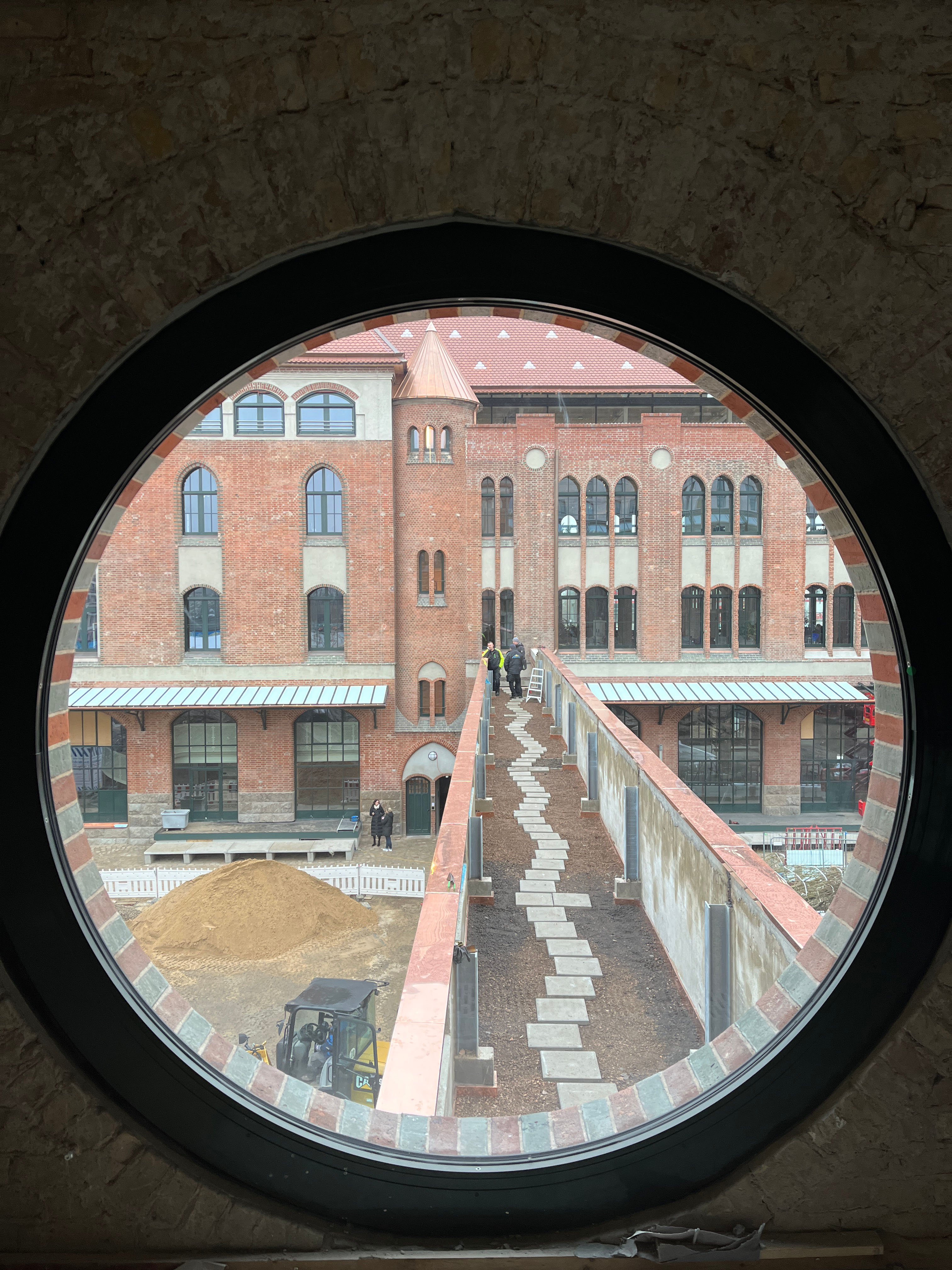 Terrassengang zwischen Abgangspackkammer und Eingangspackkammer, durch ein rundes Fenster aufgenommen.