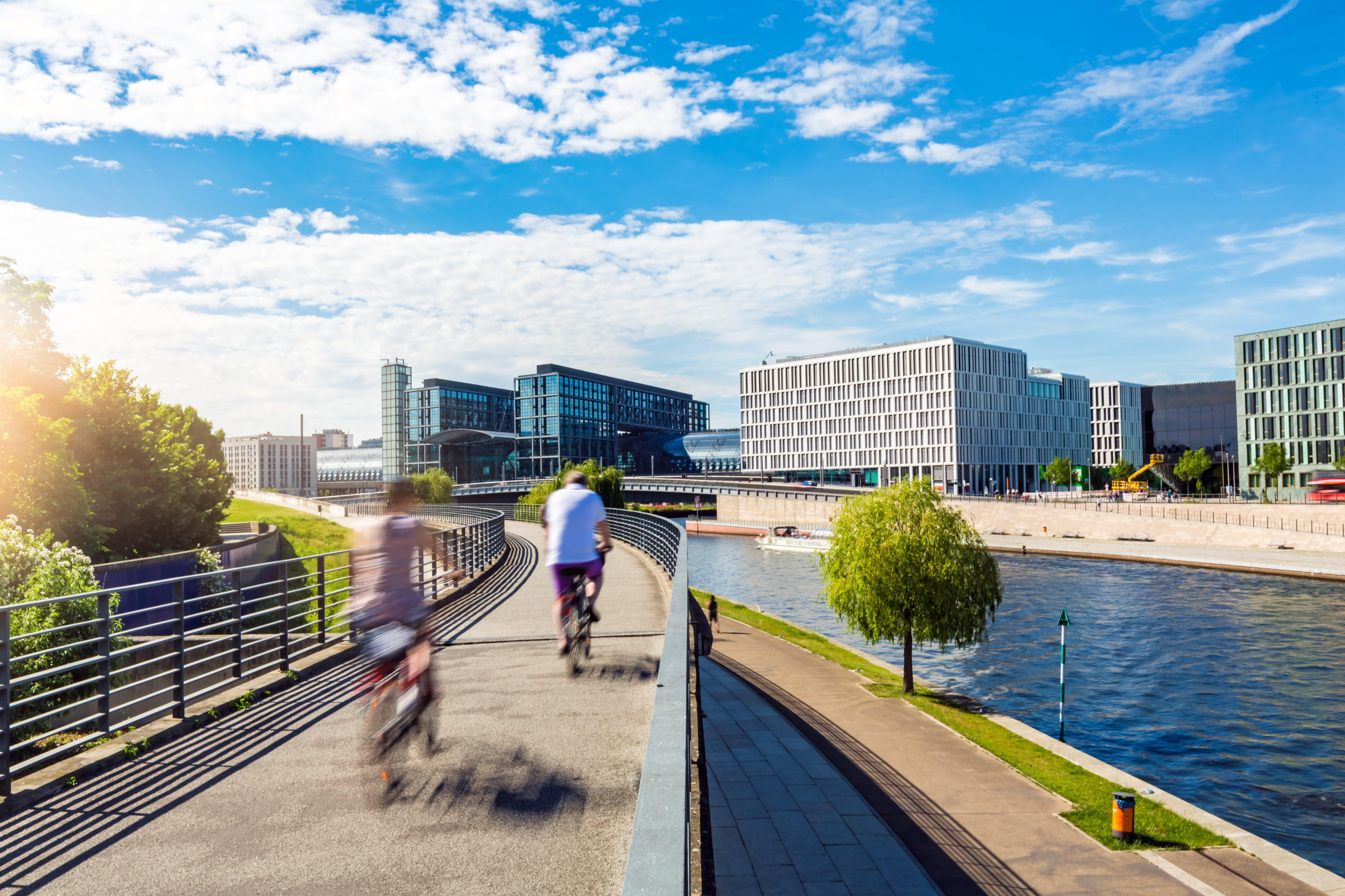 Blick auf moderne Architektur und Radfahrer entlang der Spree.