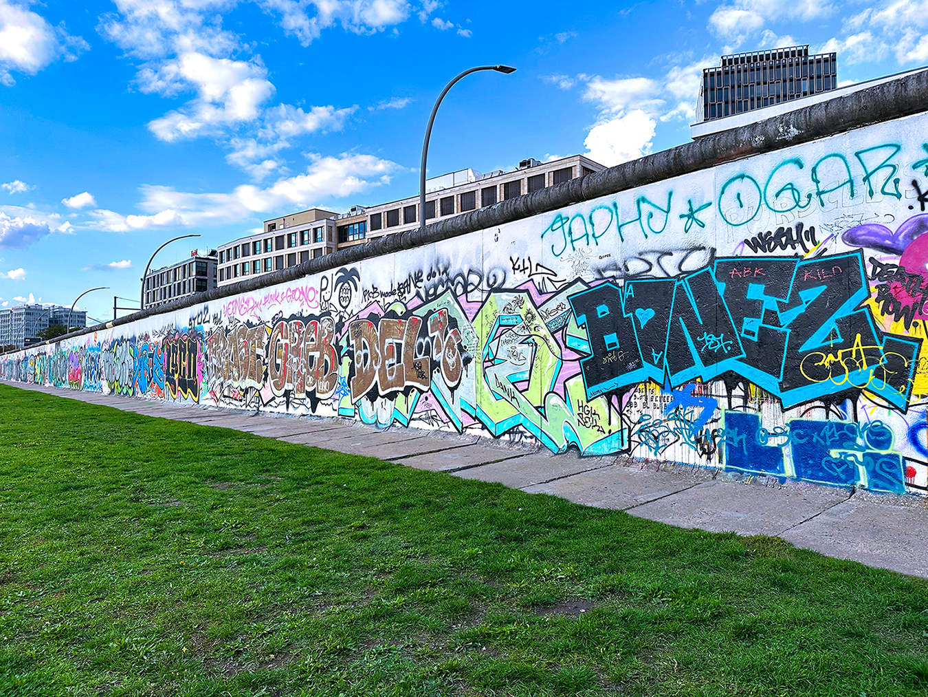 Bunte Graffiti an der Berliner Mauer unter blauem Himmel.